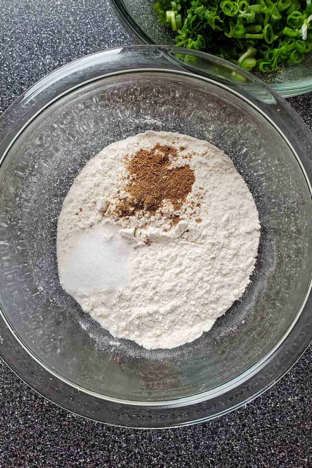 A glass bowl with AP flour, salt and 5 spice powder.