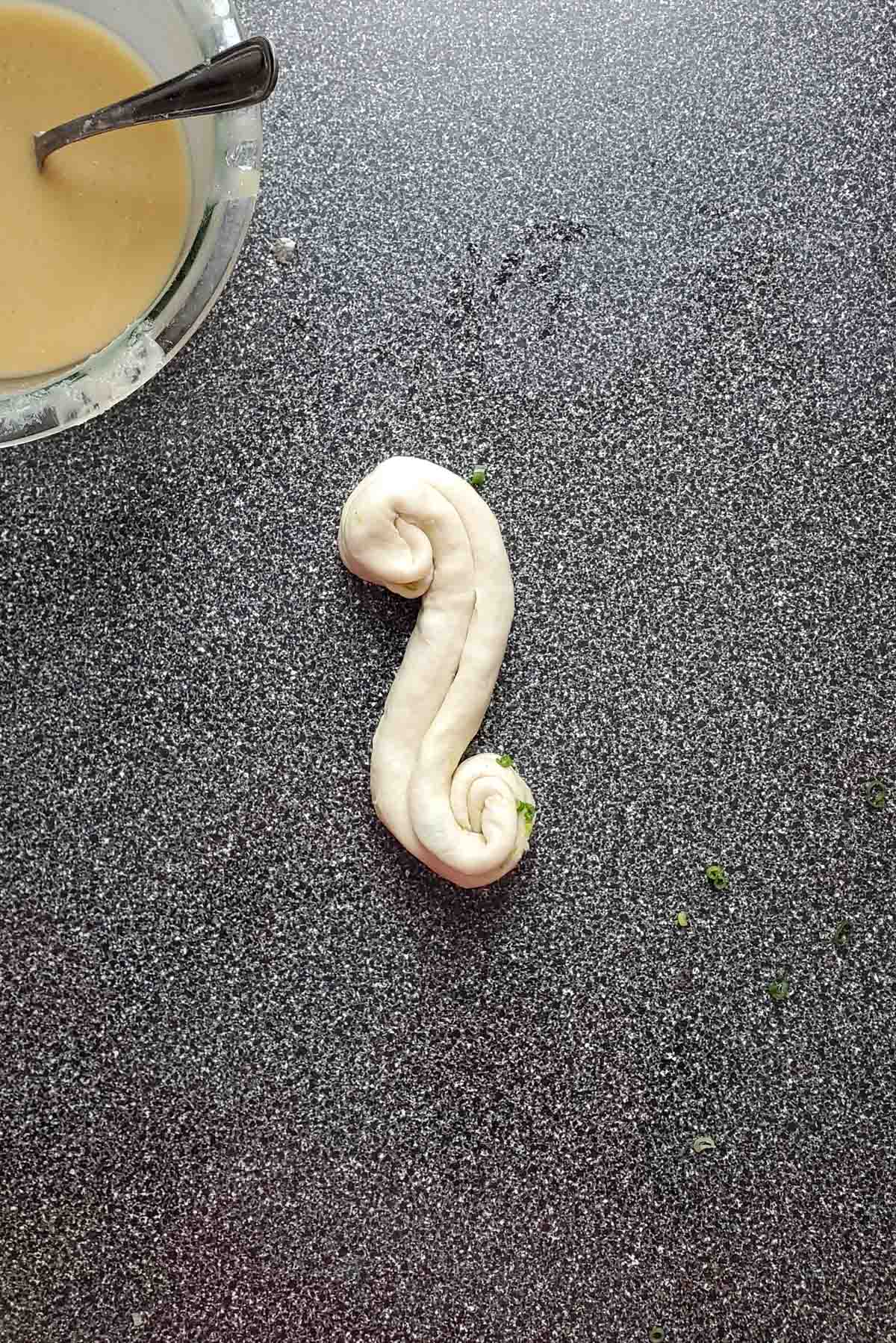The dough log being coiled from opposite ends.