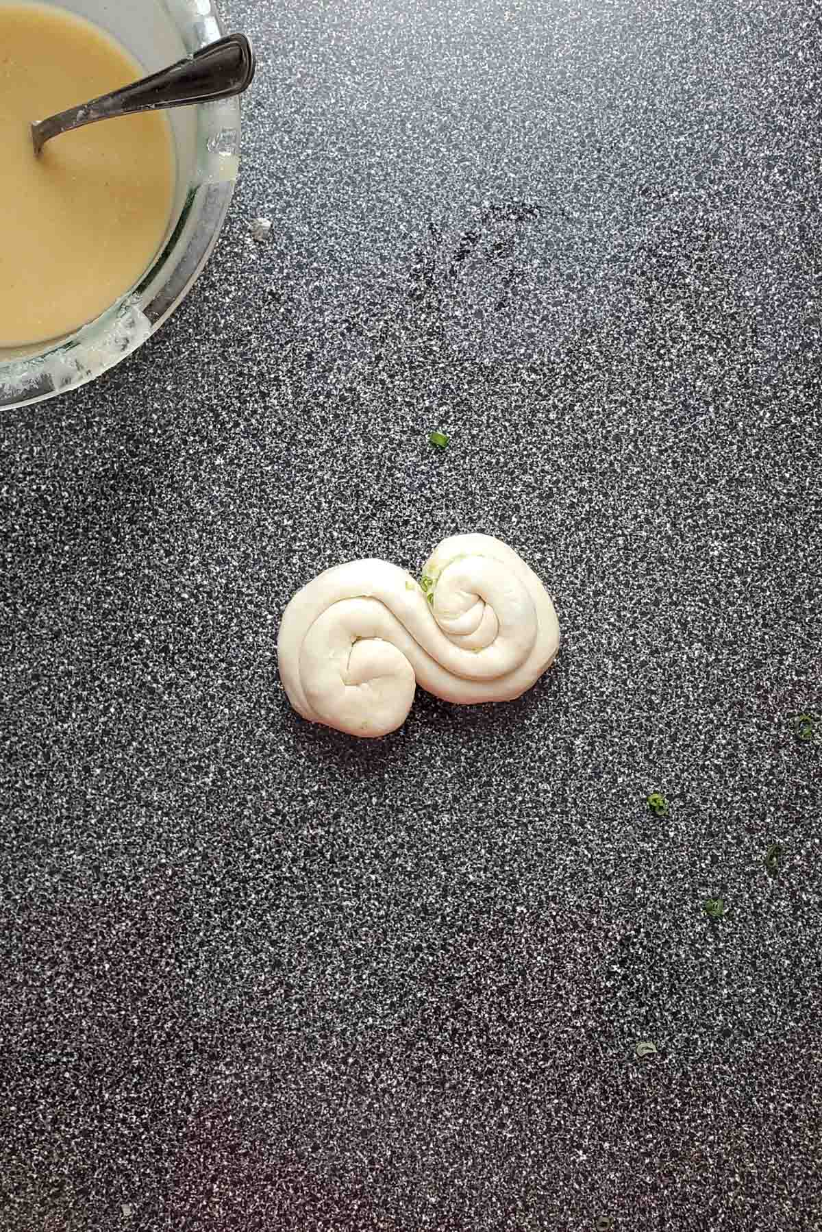 The dough coiled on both ends and meeting in the middle, forming a "s" shape.
