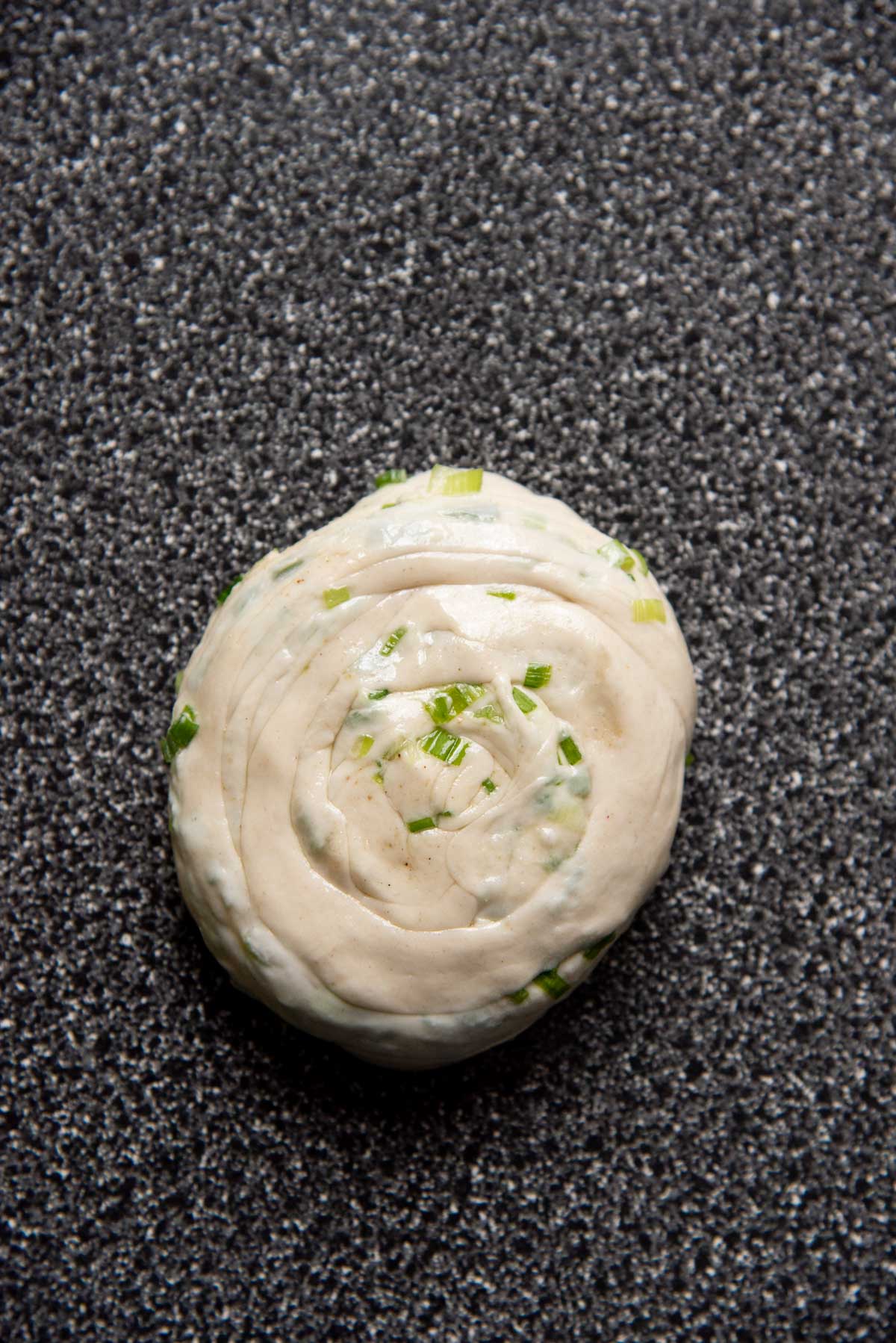 The coiled dough flattened on a speckled surface.