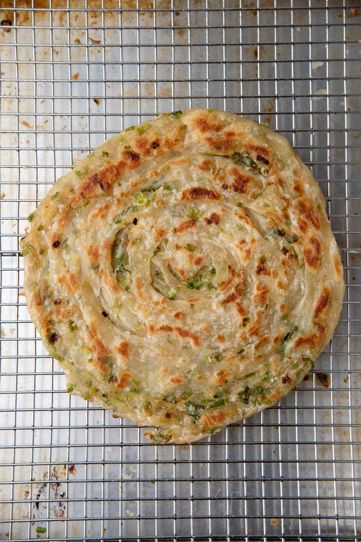 A freshly cooked pancake on a wire rack places on a metal sheetpan.
