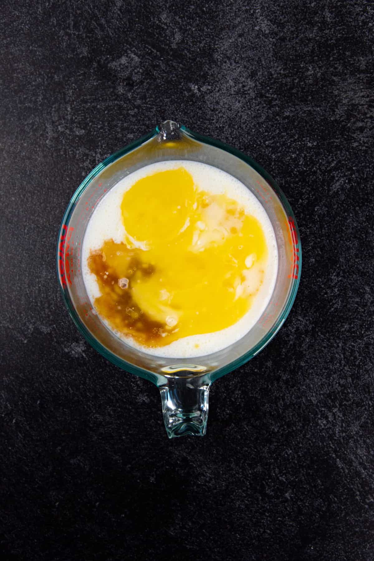 Wet ingredients added to the large jug with the buttermilk, with butter and vanilla floating on top.