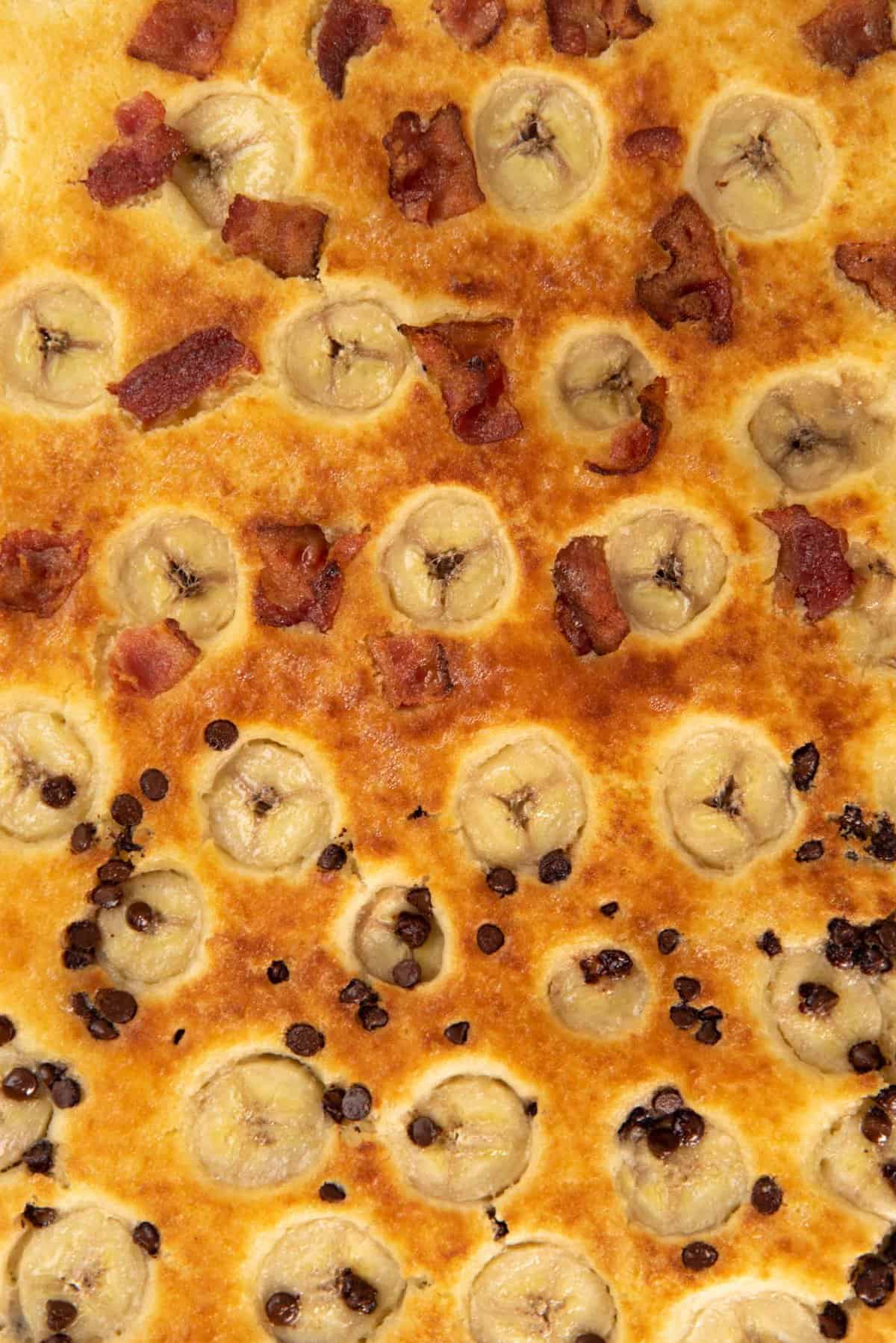 A close up of banana sheet pan pancakes - top half banana bacon pancakes and bottom half banana chocolate chip pancakes.