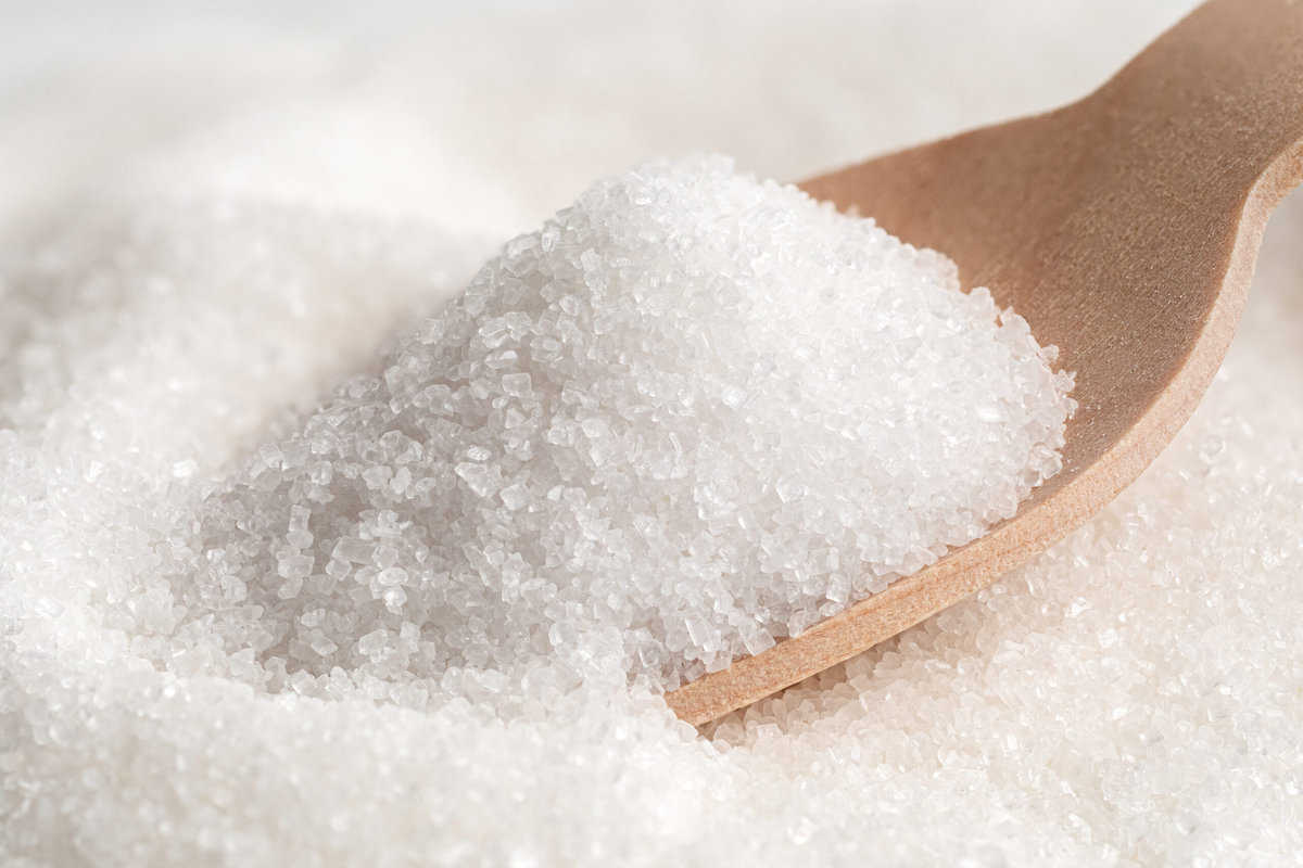 Granulates white sugar with a spoon.