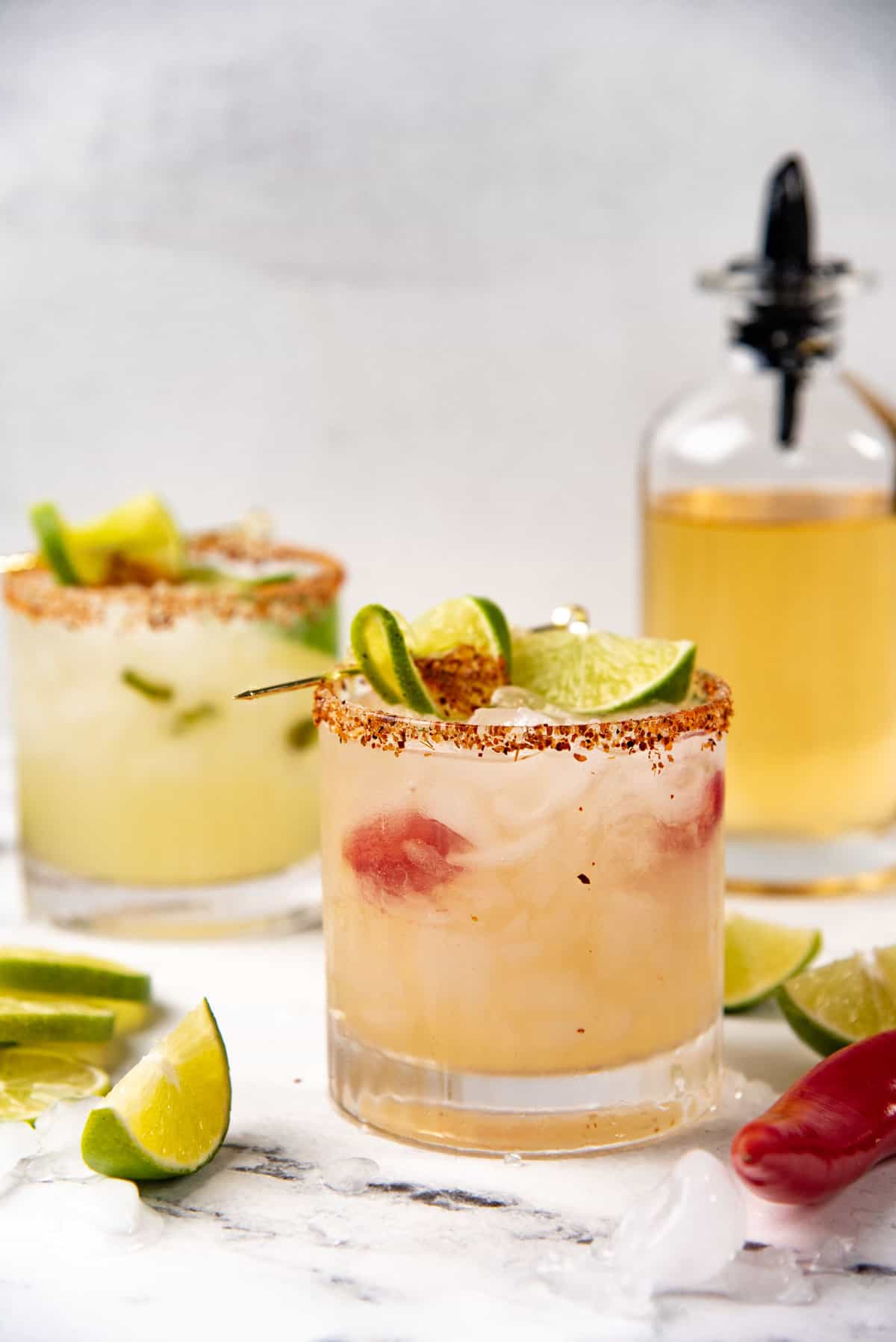 Spicy Red Jalapeno margarita served in a glass with green jalapeno margarita in the background.