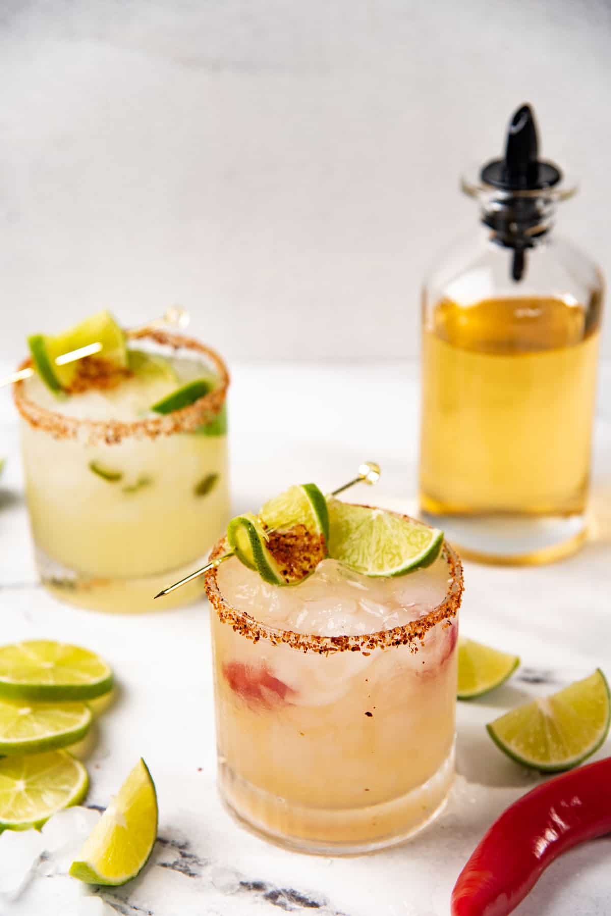 An angled view of red chili spicy margarita served in a tajin rimmed rocks glass.