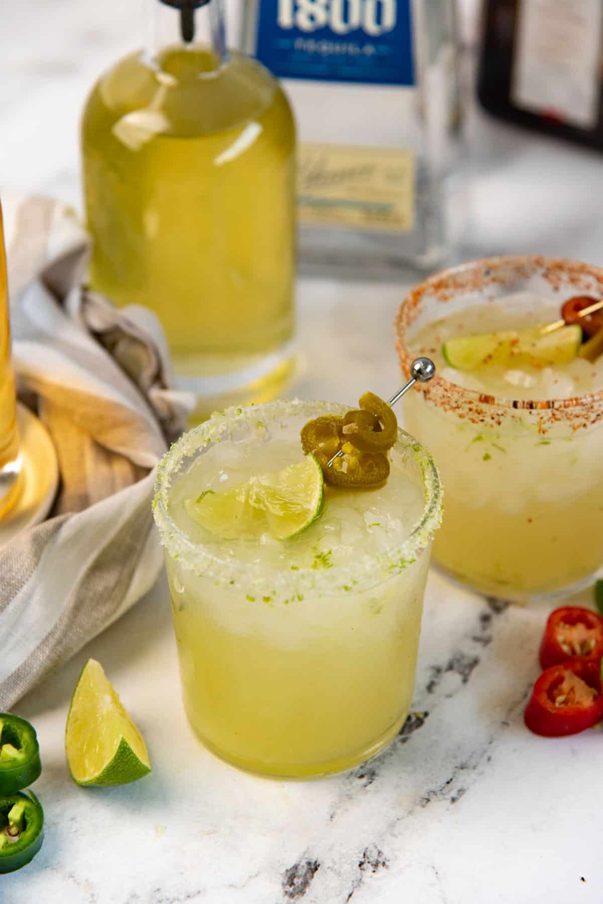 Spicy jalapeno margarita served in a rocks glass and garnished with lime and pickled jalapeno.