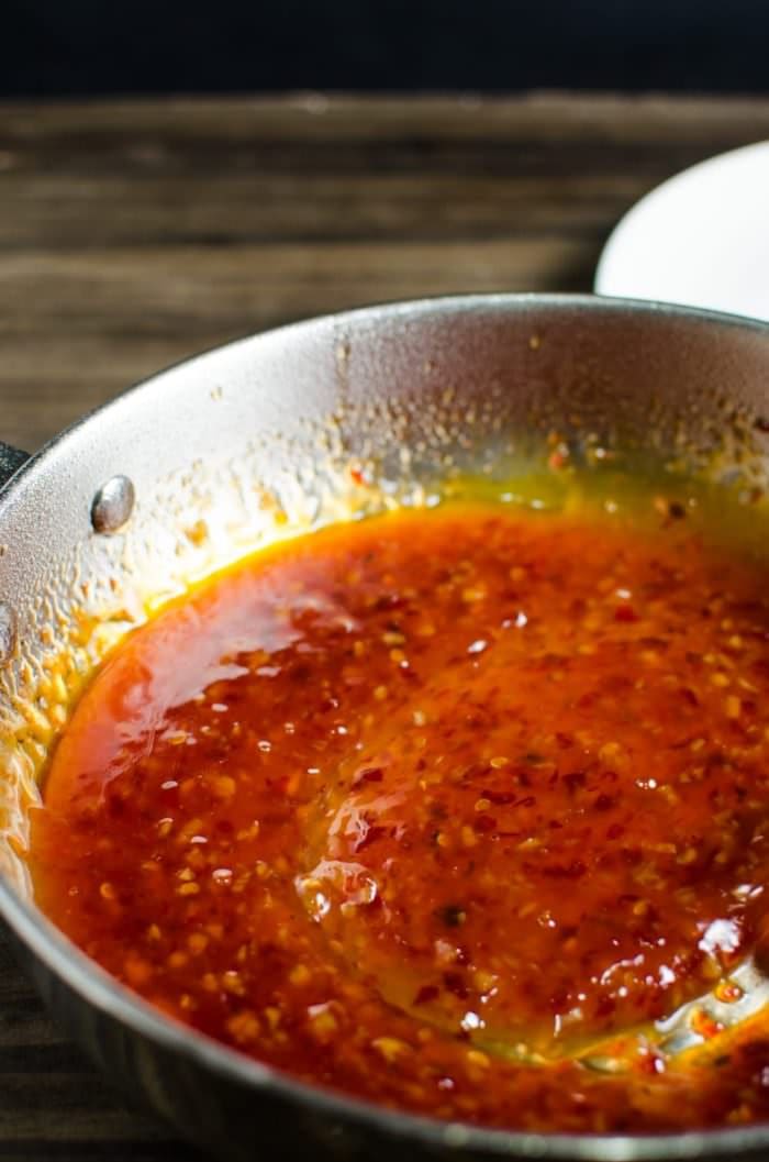 A close up of the thickened sauce stirred in a silver pan. 