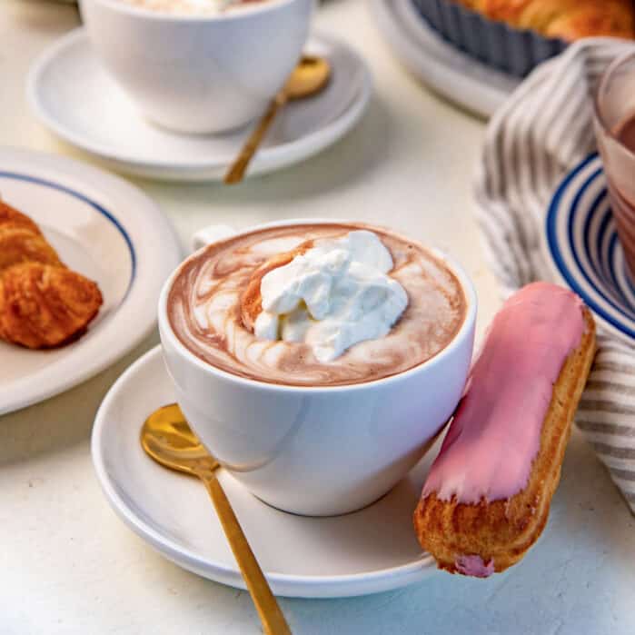 French hot chocolate (Chocolat Chaud) served with whipped cream on top and an eclair on the side.