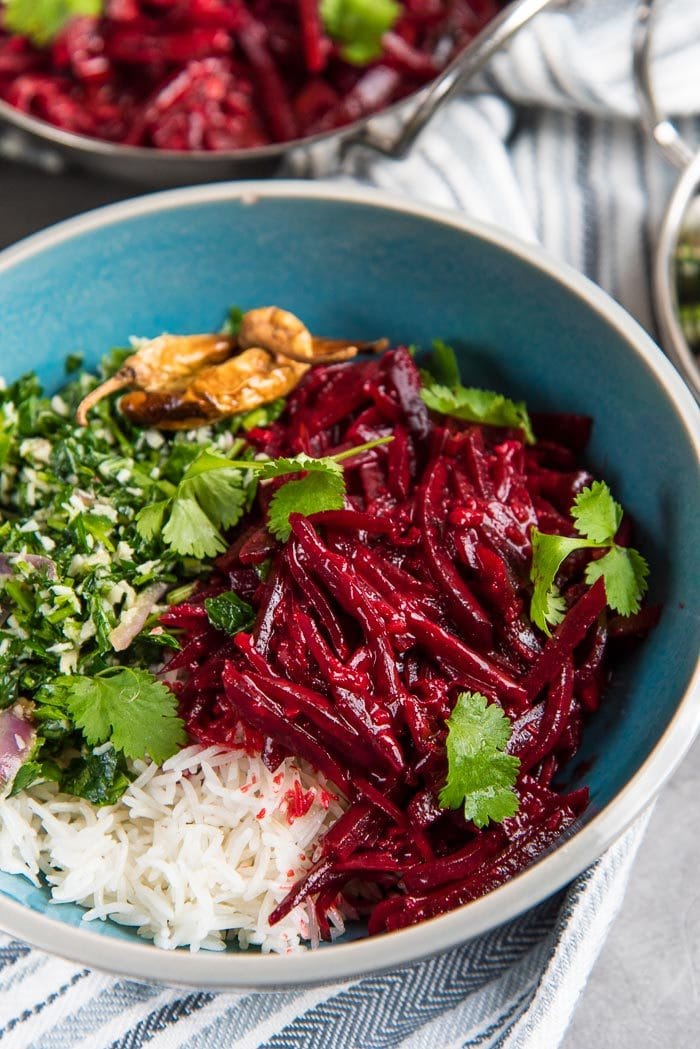 A close up of the beetroot curry served with steamed rice, with cilantro and parsley