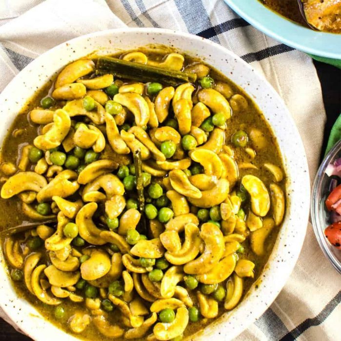 Overhead shot of vegan cashew curry with green peas served in a white bowl.