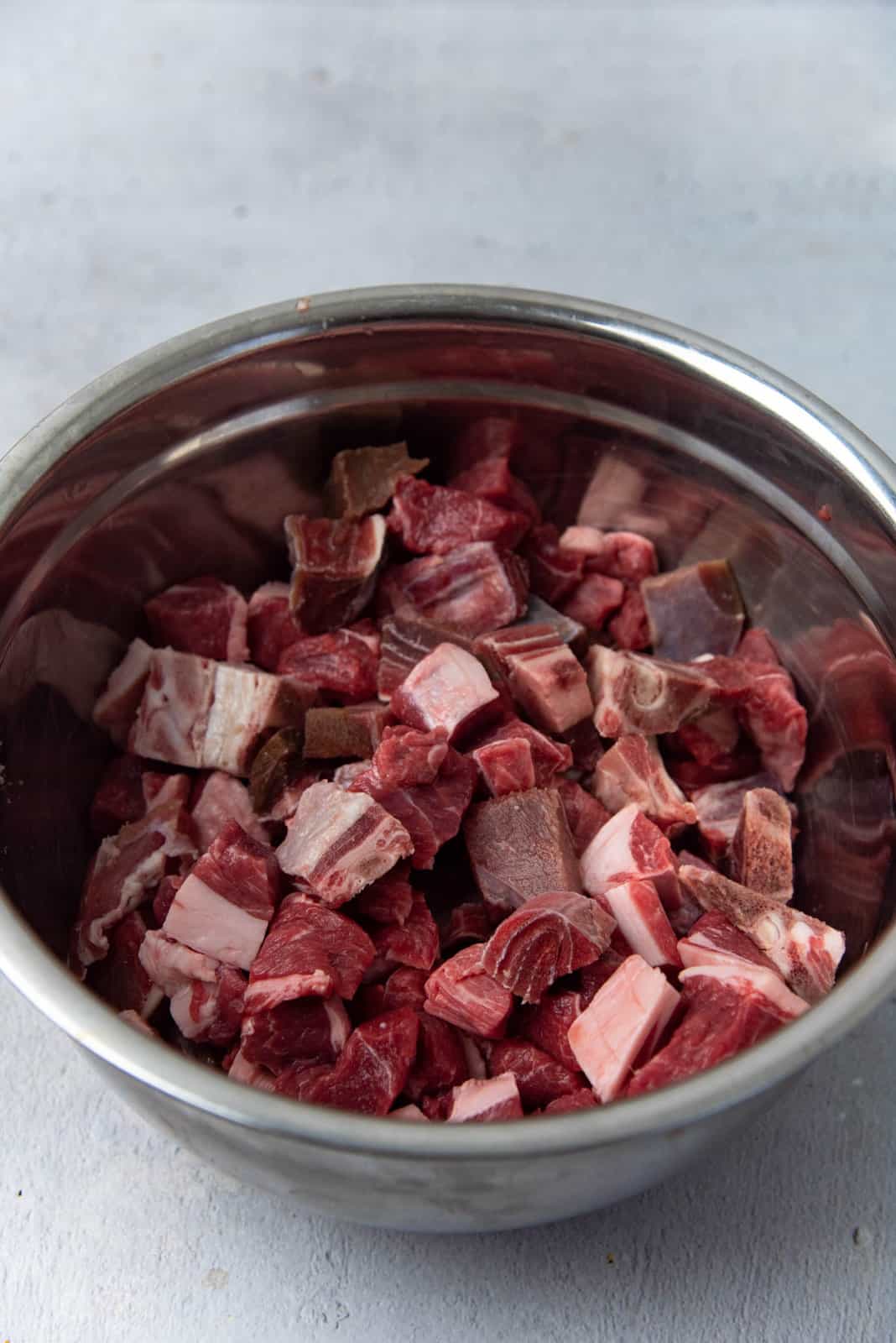 Bone-in and boneless mutton pieces in a large bowl.
