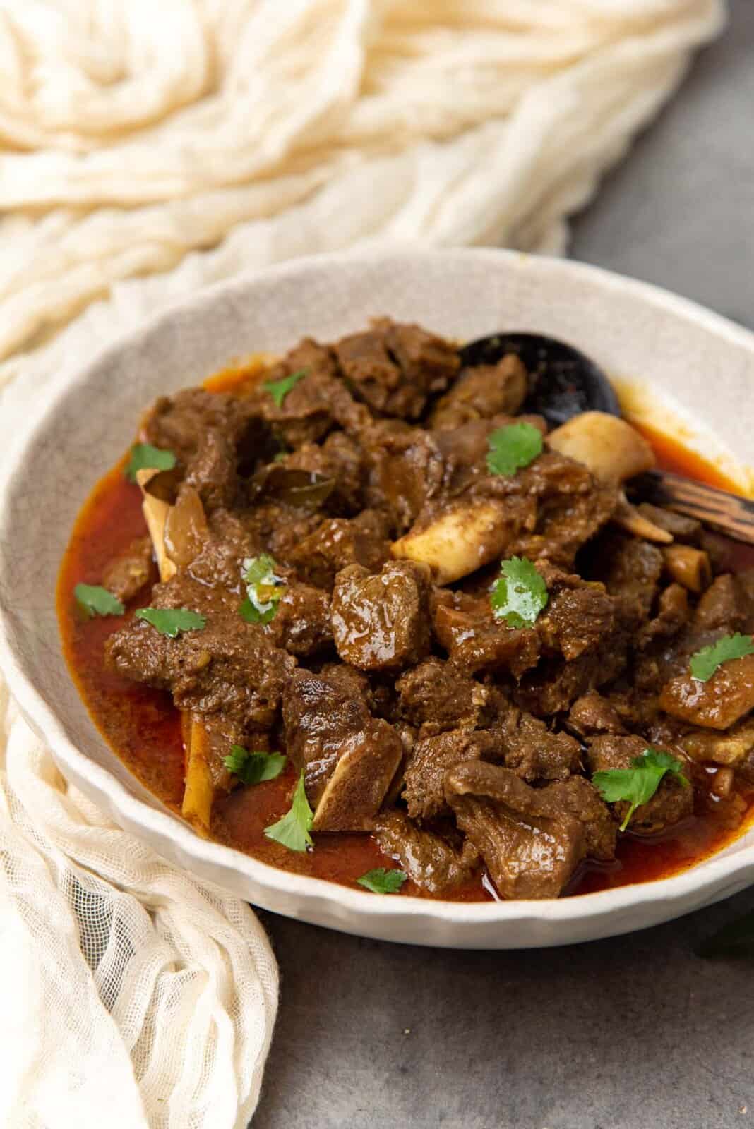 A close up of the mutton curry served in a bowl.