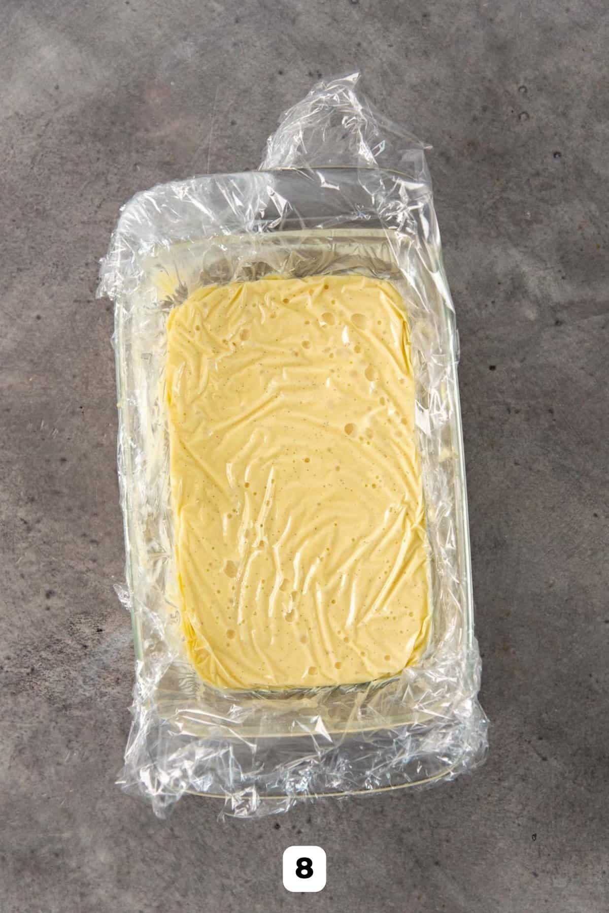 Covering the entire surface of the pastry cream with plastic wrap to prevent a skin from forming as it cools.