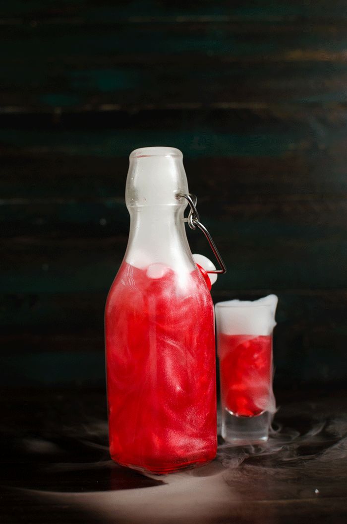 GIF of a bright red shimmering liqueur bottle with liquid nitrogen-induced smoke coming from the top.