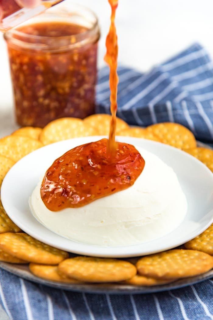 Pouring Homemade sweet chili sauce over cream cheese for a sweet chili sauce cream cheese dip. 