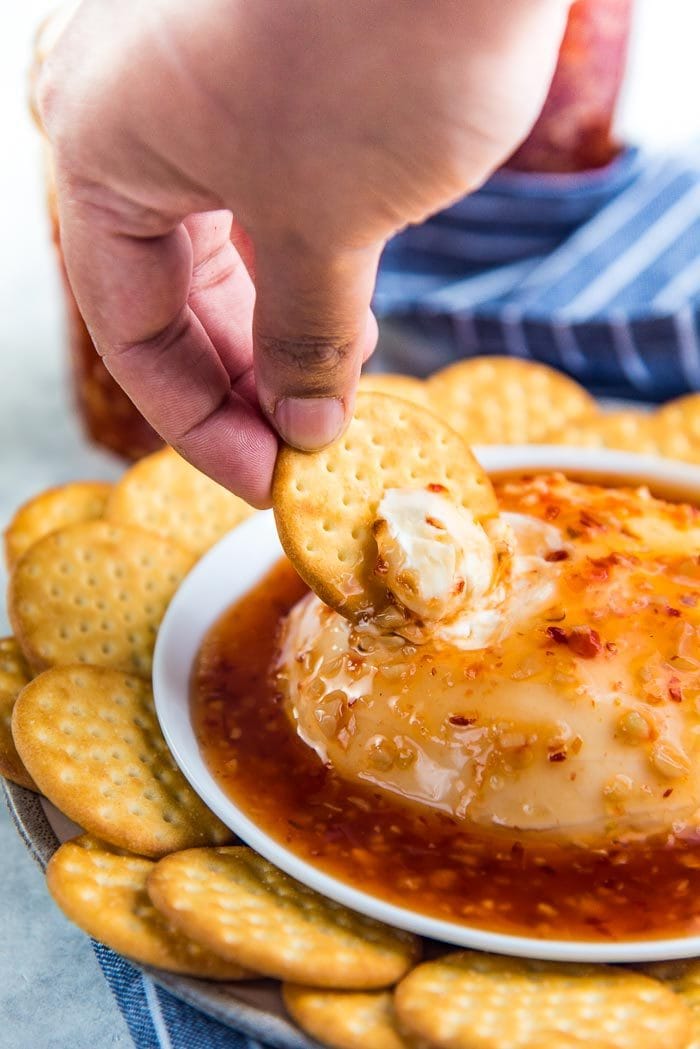 Scooping up sweet chili topped cream cheese with cheese crackers. 