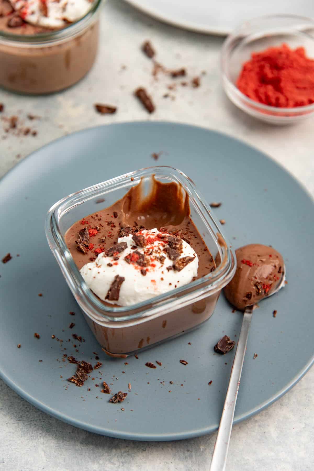 Individual serving on tofu chocolate mousse in a glass container with a spoon.