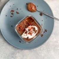 Silken tofu chocolate mousse in a glass container topped with whipped cream & chocolate shavings.