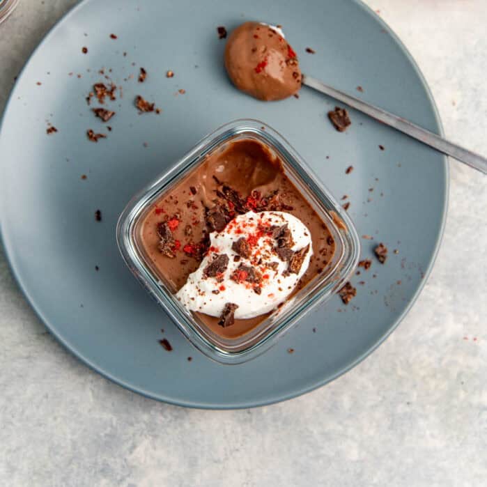 Silken tofu chocolate mousse in a glass container topped with whipped cream & chocolate shavings.