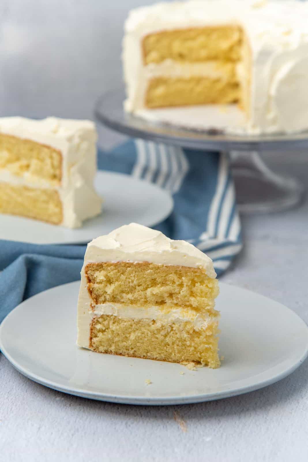 A slice of the best vanilla cake on a plate with other cake slices in the background