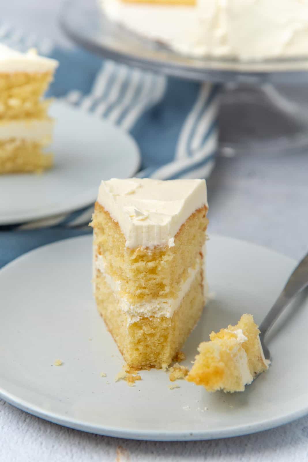 A slice of cake with a piece taken off using a fork that is placed next to the cake slice