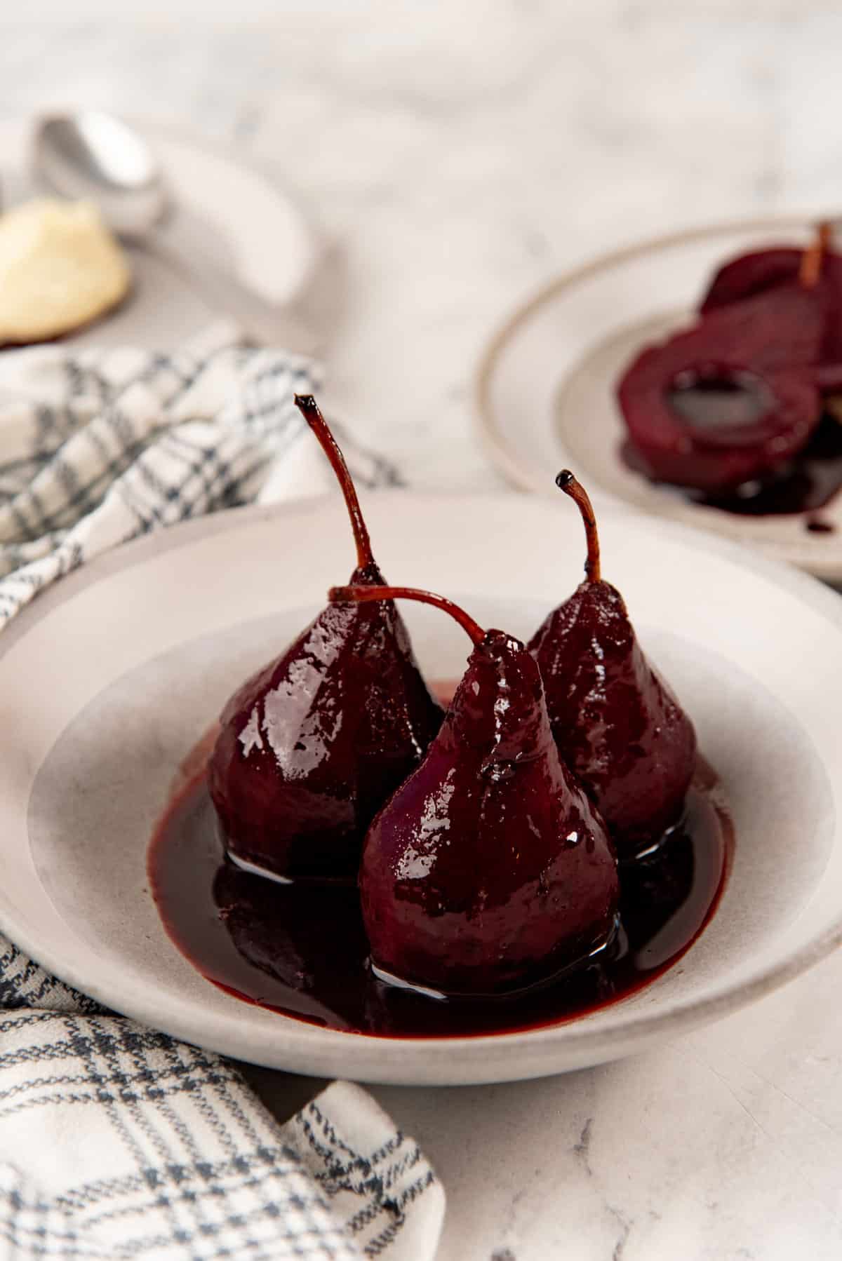 3 poached pears served in a bowl, with the syrup.